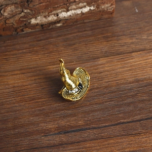 Detail of vintage gold witch hat brooch with black band and sparkling crystals on wood