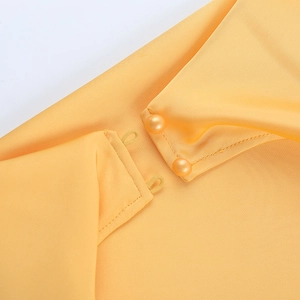 Détail d'une robe dos nu en satin jaune avec boutons en perles et fermeture élastique