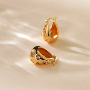 Close-up of gold-plated U-shaped earrings with sparkling cubic zirconia star details