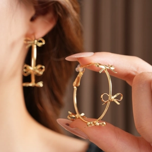 Close-up of golden hoop earrings featuring multiple 3D bows for a unique fashion look