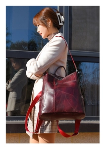Dettaglio di uno zaino in pelle bordeaux con trama e tasche laterali su una modella