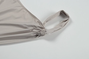 Detailed close-up of light gray knitted fabric with ruching and ring detail on the shoulder
