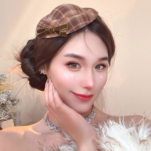 Close-up of a brown plaid beret hat with a premium dark velvet bow detail