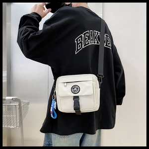 Rear view of white nylon messenger bag with black strap and circular logo on a model