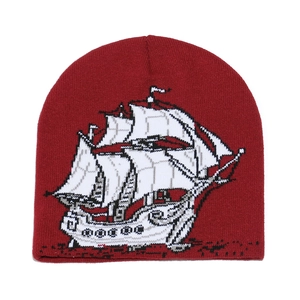 Gros plan d'un bonnet en maille bordeaux avec motif jacquard de voilier blanc