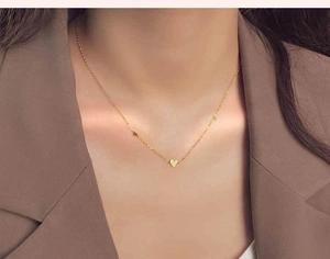 Primer plano de collar minimalista con colgante de corazón dorado sobre el cuello