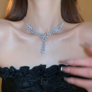 Close-up of a silver wheat leaf necklace with zirconia fringe on a model neck