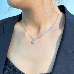 Nahaufnahme eines silbernen Hohlkugelanhängers an einer glatten Schlangenkette