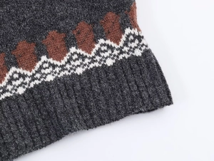 Macro detail of ribbed cuffs and Nordic jacquard pattern on a grey knit sweater