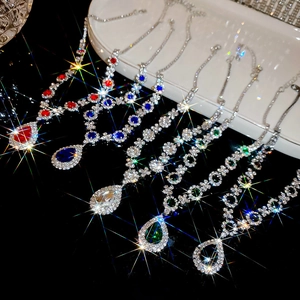 Macro shot of shimmering teardrop crystal necklaces in six vibrant colors on dark surface