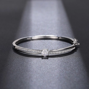 Detail of silver crossover bangle featuring a central round zircon and pavé diamonds