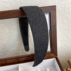 Détail d'un serre-tête large en denim noir avec texture sergé fine sur boîte en bois