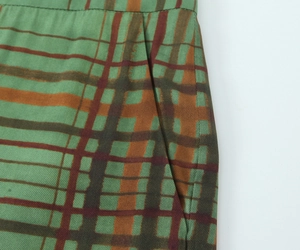 Detail of dark green plaid fabric showing high-density woven texture and pocket stitching