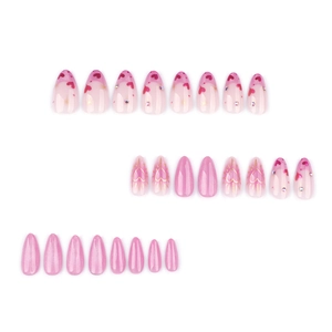 Pink cat eye almond press-on nails with glitter, red hearts, and gold starburst accents