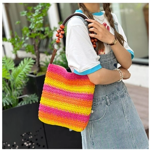 Close-up of rainbow straw woven handbag with handmade colorful wooden bead handle