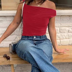 Detail of red off-shoulder ruched top paired with blue jeans for a trendy casual summer look