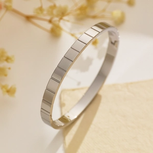 Dettaglio del bracciale in acciaio argento con trame geometriche a scanalature rettangolari