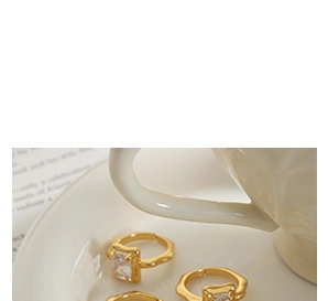 Close-up of three 18K gold plated rings with square crystals on a white ceramic plate
