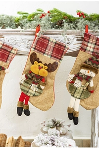 Close-up of knit Christmas stockings with 3D elk and snowman figures on a mantel