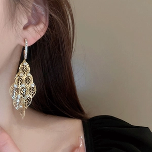 Detail view of gold leaf fringe earrings with crystal pavé on a model
