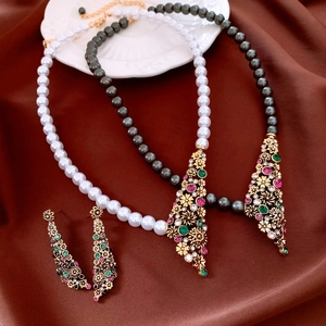 Dettaglio di set di collane vintage con perle e pendenti a fiore in oro e gemme