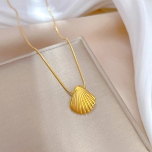 Detail of a gold shell pendant with textured ridges on a sleek snake chain necklace