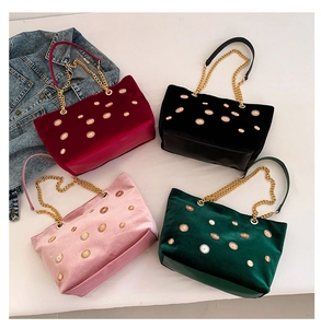 Vue détaillée de sacs cabas en velours bordeaux, noir, rose et vert avec détails dorés