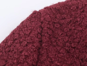 Close-up of curly wool texture on wine red coat showing premium bouclé fabric detail