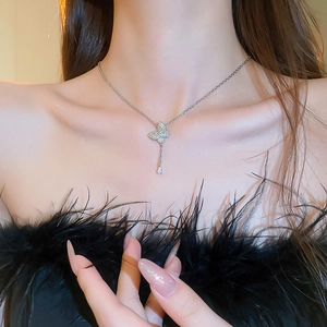 Detail of silver butterfly necklace with teardrop gemstone worn by a model