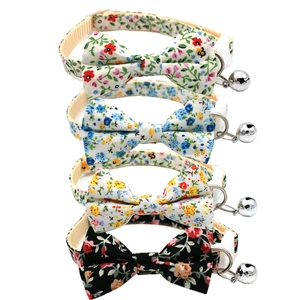 Detail of four floral pet collars with bowknots and metal bells on white background