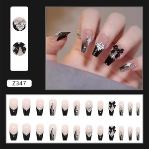 Detail view of long coffin press-on nails with 3D black bows and sparkling crystal hearts