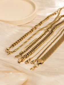 Macro view of assorted 18K gold plated stainless steel Cuban and snake chain bracelets