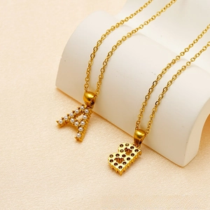 Detail of gold titanium steel pendants with initial A and B featuring pearl inlay