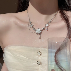 Detailed view of silver flower necklace with zircons and tassels worn by a model
