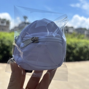Detailed view of mini white canvas backpack coin purse with silver zipper in hand