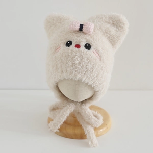 Detail of plush beige infant earflap hat with cute embroidery and pink plaid bow