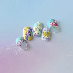 Detail view of 3D embossed rabbit and bow charms on pastel multi-color handmade press-on nails