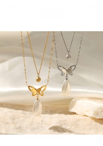 Detail of 14K gold and silver layered necklaces with butterfly charms and drop pearls