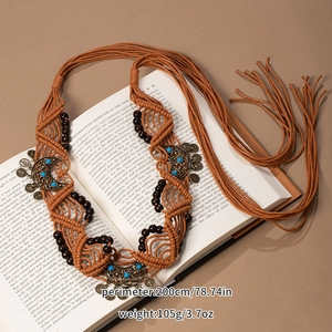 Detail of bohemian handmade woven belt with turquoise beads laid on a vintage book