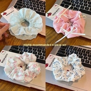 Detailed view of 4-piece set floral and lace scrunchies on a soft decorative background