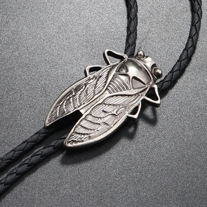 Detail of vintage silver cicada bolo tie pendant with black braided leather cord