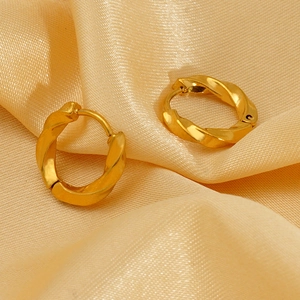 Elegant gold plated twisted hoop earrings displayed on soft champagne silk fabric