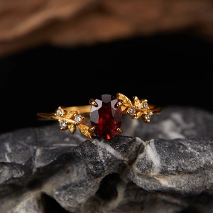 Detail view of gold S925 silver ring with red garnet on grey rock texture