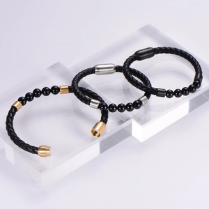 Dettaglio di bracciali in pelle intrecciata con chiusure magnetiche in oro argento e nero