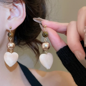 Detail view of heart-shaped earrings with tiger eye beads and pearls in vintage style