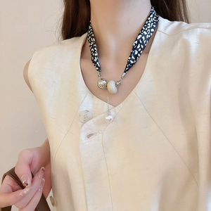 Détail du collier foulard en soie à imprimé léopard avec perles argentées et perle