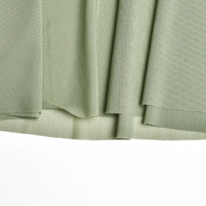 Gros plan détaillé de la texture du tissu en maille vert clair respirant et des plis