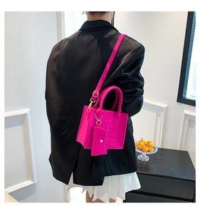Detail of bright pink crocodile pattern handbag with matching mini coin purse attachment