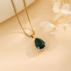 Close-up of a gold box chain necklace with a pear-shaped green zircon halo pendant