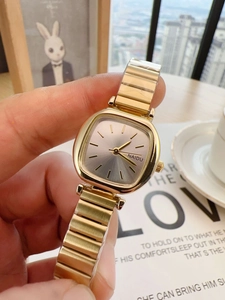 Close-up of a women's gold square watch with metal band on a magazine background
